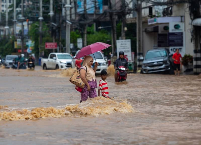 A woman and a boy walk along a flooded street in the Chang Khlan area due to the Ping River overflowing into urban areas after continuous rainfall in Chiang Mai. Pongmanat Tasiri/SOPA Images via ZUMA Press Wire/dpa