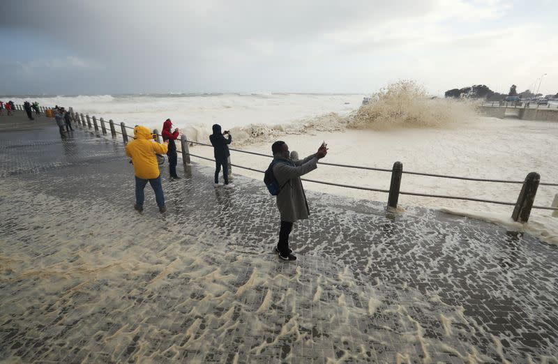 People watch huge swells as a cold front moves in over Cape Town, South Africa