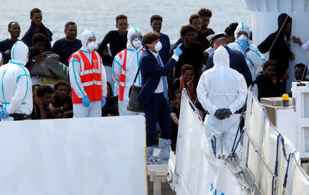 FILE PHOTO: An Italian official gestures as migrants wait to disembark from Italian coast guard vessel "Diciotti" at the port of Catania, Italy, August 22, 2018. REUTERS/Antonio Parrinello