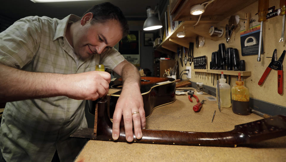 Jacob Tuel, owner of Burning River Guitars, repairs the neck on a guitar, Monday, June 10, 2019, in Akron, Ohio. Tuel named his guitar shop after the 1969 blaze on the Cuyahoga River, in Cleveland. (AP Photo/Tony Dejak)
