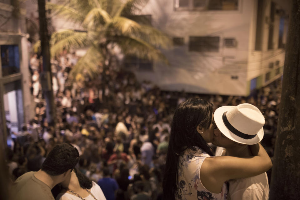 This Sept. 7, 2012 photo shows couples kissing as people gather to listen to live Samba music in a plaza called "Pedra do Sal" ("Stone of Salt") in Rio de Janeiro, Brazil. Rio's signature percussion-driven rhythm can be heard in classy indoor music venues, sure, but old-school samba circles can pop up without notice. (AP Photo/Felipe Dana)
