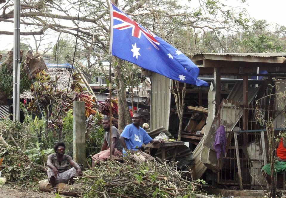 Local residents sit outside their damaged homes surrounded by debris on a street after Cyclone Pam hit Port Vila, the capital city of the Pacific island nation of Vanuatu