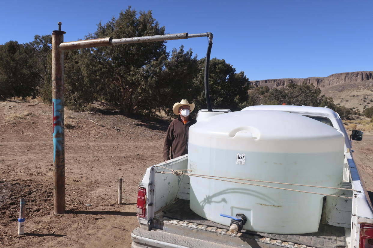 FILE - Phillip Yazzie waits for a water drum in the back of his pickup truck to be filled in Teesto, Ariz., on the Navajo Nation, on Feb. 11, 2021. The Supreme Court appears to be split in a dispute between the federal government and the Navajo Nation over water from the drought-stricken Colorado River. The high court heard arguments Monday, March 20, 2023, in a case that states argue could upend how water is shared in the Western U.S. if the court sides with the tribe. (AP Photo/Felicia Fonseca, File)