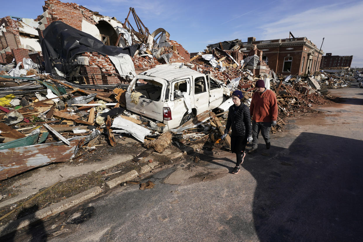 FILE -People survey damage from a tornado in Mayfield, Ky., on Saturday, Dec. 11, 2021. Tornadoes and severe weather caused catastrophic damage across multiple states killing several people overnight. The holiday season tragedy killed 81 people in Kentucky and turned buildings intomounds ofrubble as damage reached into hundreds of millions of dollars.(AP Photo/Mark Humphrey, File)