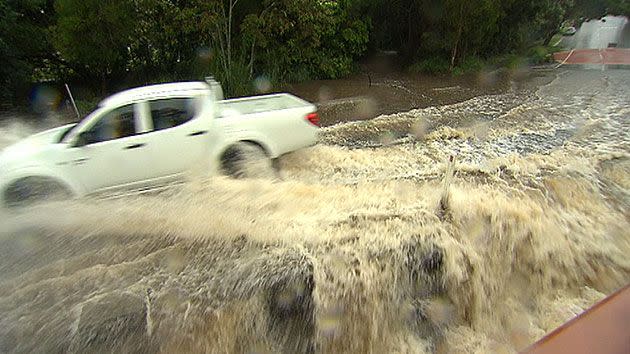 Car driving through water at Bardon after the Ithaca Creek broke its banks. Source: 7News