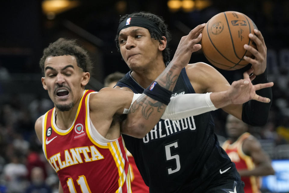 Atlanta Hawks' Trae Young, left, fouls Orlando Magic's Paolo Banchero (5) as he goes in for a shot during the second half of an NBA basketball game, Wednesday, Dec. 14, 2022, in Orlando, Fla. (AP Photo/John Raoux)