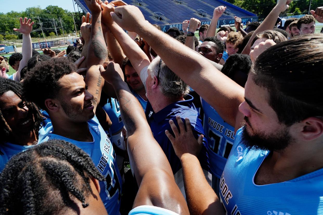 The URI football team gathers at Meade Stadium for photo day on Thursday as players prepare for a new season under coach Jim Fleming, who brings the team together before they were finished for the day.