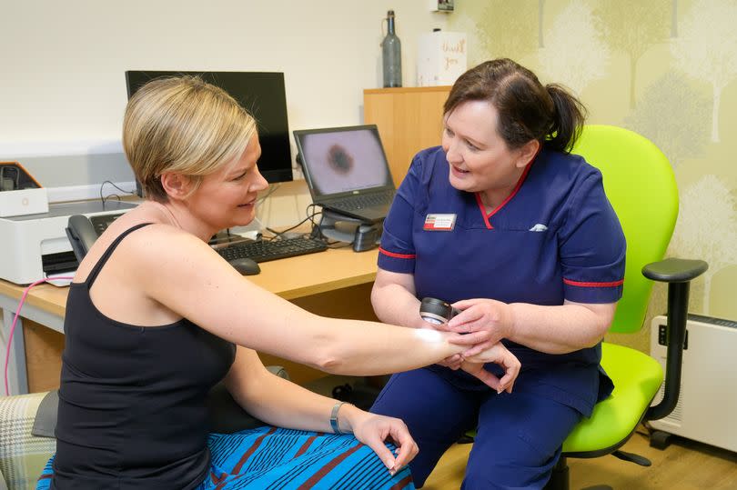 Action Cancer Ambassador Lyn Stevenson has her skin examined by Action Cancer’s Senior Skin Cancer Specialist Iona McCormack using a Dermatoscope in the clinic at Action Cancer House, Belfast