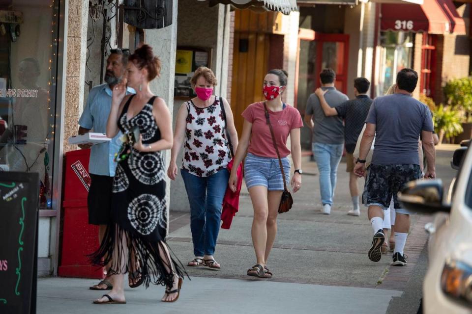 Shoppers – some with masks, others without – walk along store fronts in downtown Placerville on Friday, June 26, 2020. California has ordered everyone to wear a face mask while in public as it continues to try and re-open after more than 3 months of lockdown during the coronavirus pandemic.