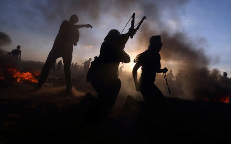 Palestinians hurl stones at Israeli troops during a protest calling for lifting the Israeli blockade on Gaza and demanding the right to return to their homeland, at the Israel-Gaza border fence, in the southern Gaza Strip September 21, 2018. REUTERS/Ibraheem Abu Mustafa