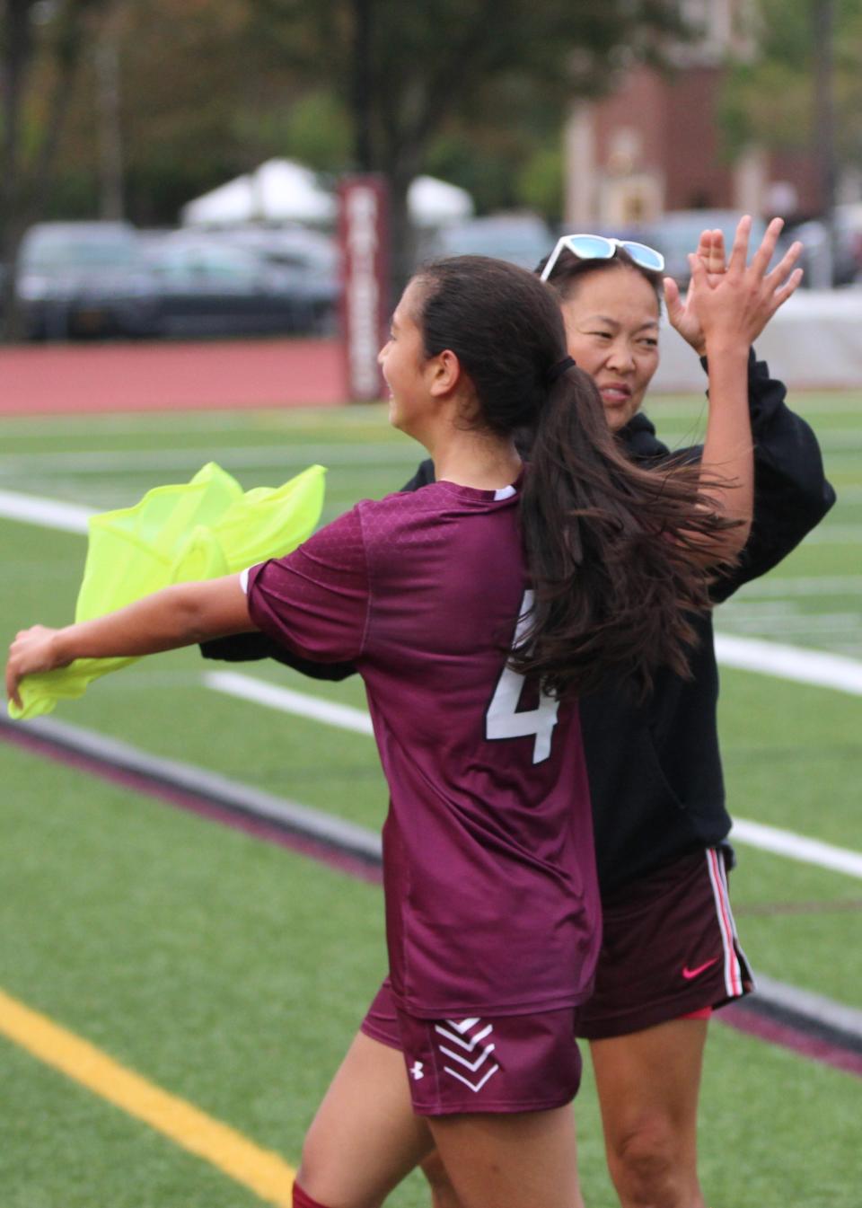 Scarsdale coach Mindy Genovese high-fives Mia Laboy as she comes off the field.