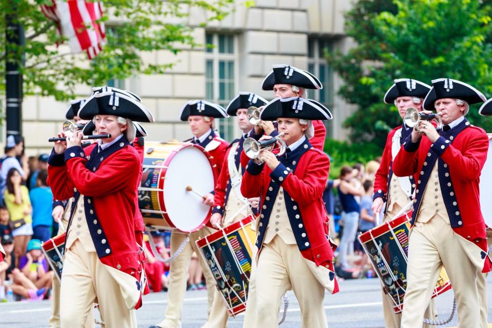 4th of july parade, parade members in uniforms with drums and a trumpet, good housekeeping's favorite 4th of july activities