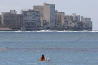 People swim off Waikiki Beach in Honolulu on Saturday, March 28, 2020. Like many cities across the world, Honolulu came to an eerie standstill this weekend as the coronavirus pandemic spread throughout the islands. But Hawaii officials went beyond the standard stay-at-home orders and effectively flipped the switch on the state's tourism-fueled economic engine in a bid to slow the spread of the virus. As of Thursday, anyone arriving in Hawaii must undergo a mandatory 14-day self-quarantine. The unprecedented move dramatically reduced the number of people on beaches, in city parks and on country roads where many people rely on tourism to pay for the high cost of living in Hawaii. (AP Photo/Caleb Jones)