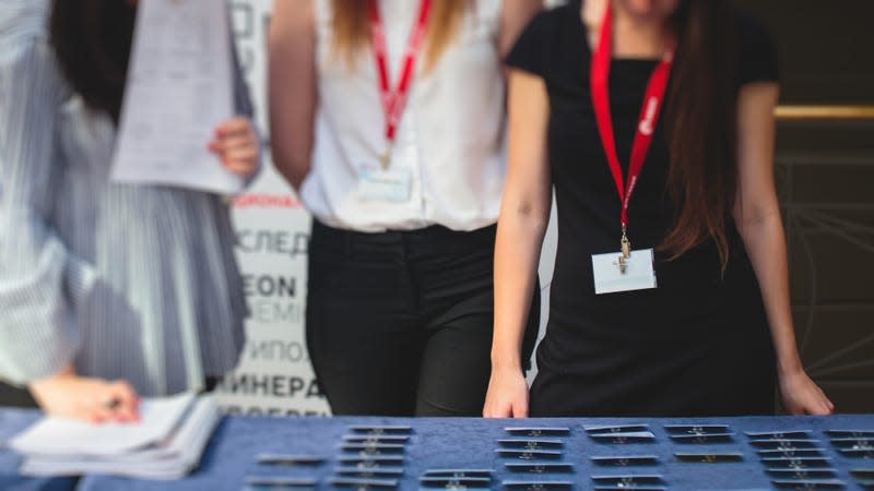 People picking up badges at a conference registration table