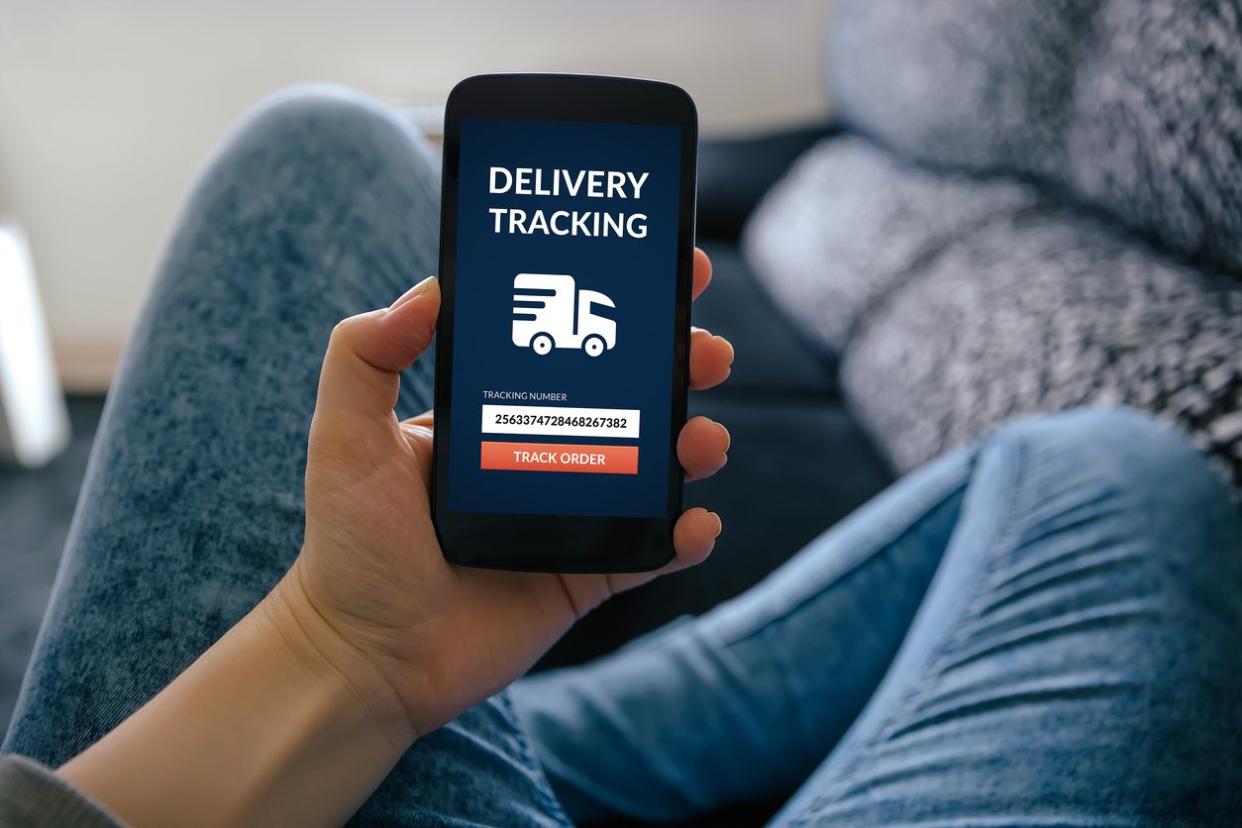 Woman holding smart phone with delivery tracking concept on screen