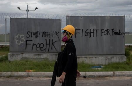 A protester walks past a graffiti at Hong Kong International Airport, in Hong Kong