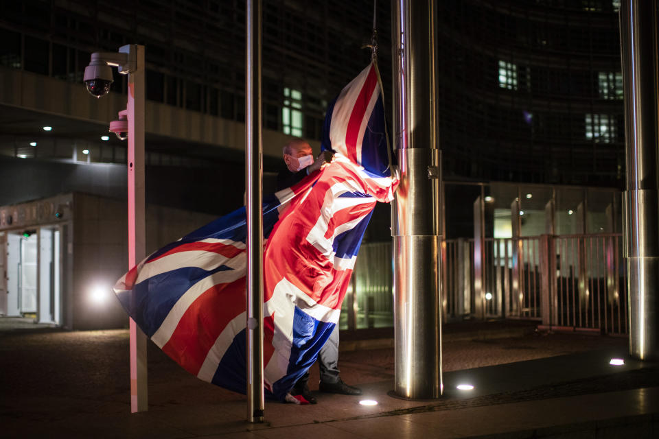 FILE - In this Wednesday, Dec. 9, 2020 file photo, a worker raises the Union Flag prior a meeting between European Commission President Ursula von der Leyen and British Prime Minister Boris Johnson at EU headquarters in Brussels. Relations between the European Union and recently departed Britain took another diplomatic dip on Wednesday, March 10, 2021 when the EU envoy in London was summoned to explain comments that Britain had issued a vaccine export ban. (AP Photo/Francisco Seco, File)