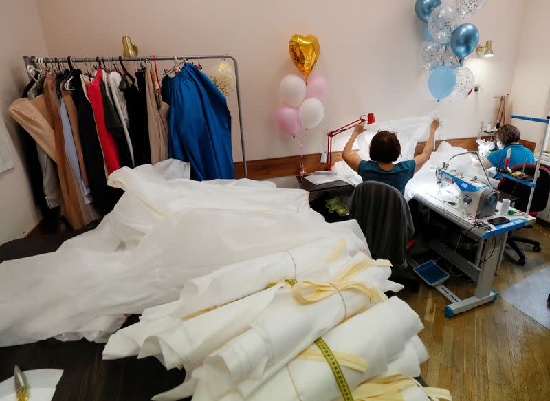 Employees sew medical protective coveralls in the show room of Ukrainian fashion designer Frolov in Kiev