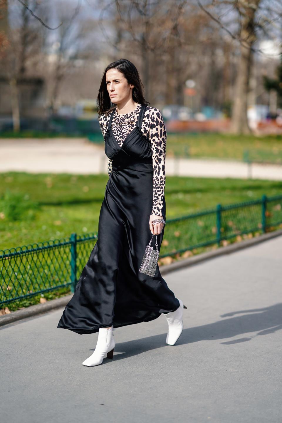 PARIS, FRANCE - FEBRUARY 28: A guest wears a lustrous black satin flowing strappy dress, a leopard print top, white boots, a small metal mesh bag, outside Paco Rabanne, during Paris Fashion Week Womenswear Fall/Winter 2019/2020, on February 28, 2019 in Paris, France. (Photo by Edward Berthelot/Getty Images)