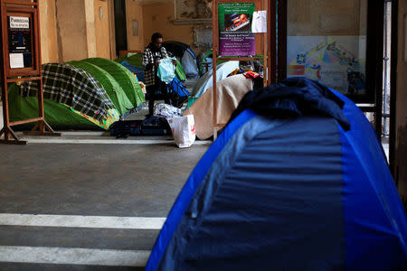 A woman folds clothes next to her tent in the portico of the Basilica of the Santi Apostoli, where she lives after being evicted from an unused building along with other families in August 2017, in Rome, Italy January 29, 2018. REUTERS/Tony Gentile