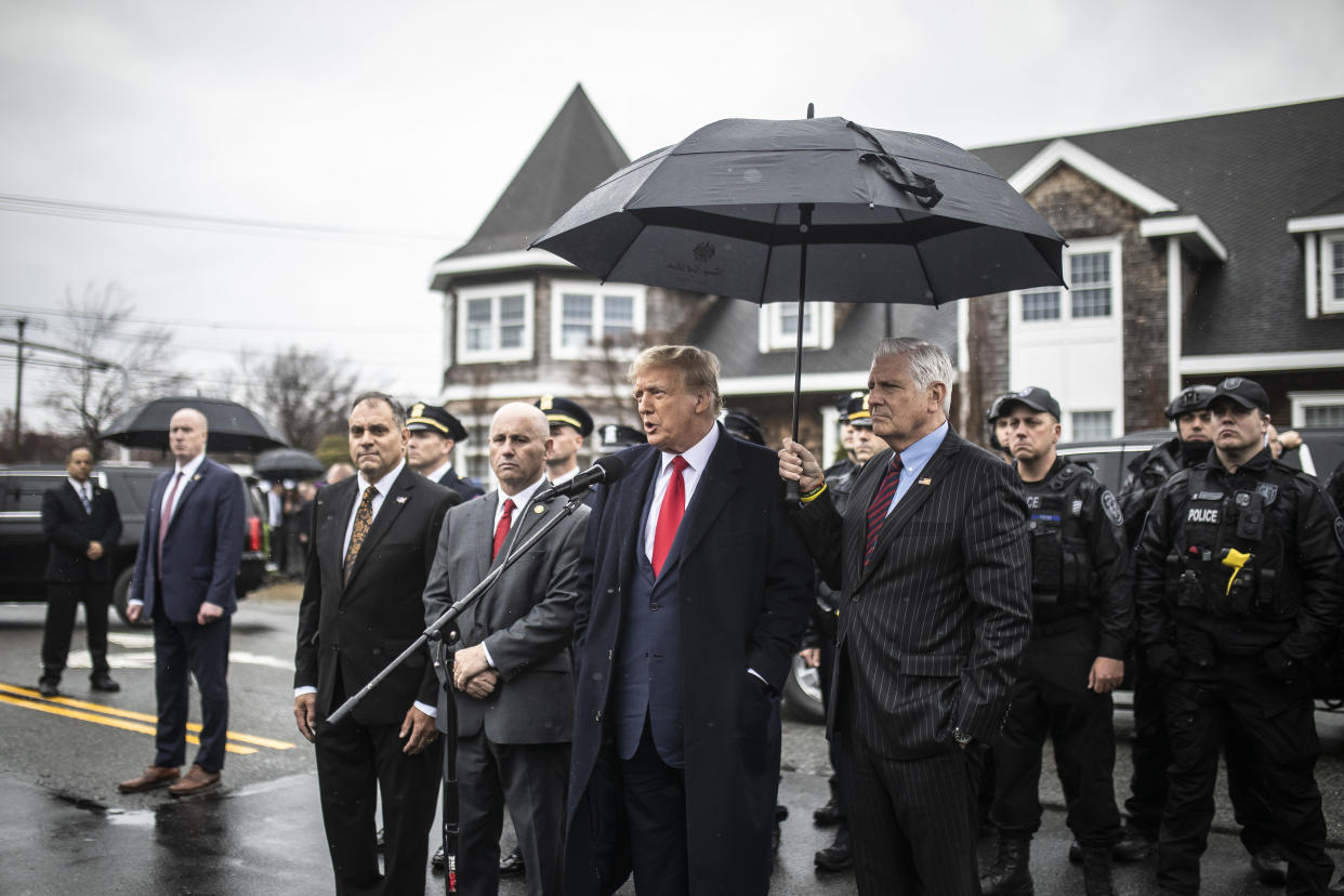 Bruce Blakeman, the Nassau County executive, holds an umbrella over former President Donald Trump as Trump speaks in Massapequa Park, N.Y., March 28, 2024. (Dave Sanders/The New York Times)