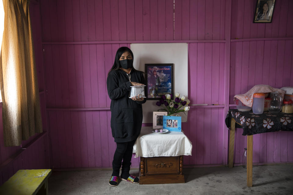 Joselyn García posa para una foto sosteniendo la urna que contiene los restos cremados de su madre, quien murió de síntomas relacionados con el nuevo coronavirus, en su casa en Lima, Perú, el lunes 29 de junio de 2020. Joselyn, de 25 años, contruyó un altar en honor a su mamá. (AP Foto/Rodrigo Abd)