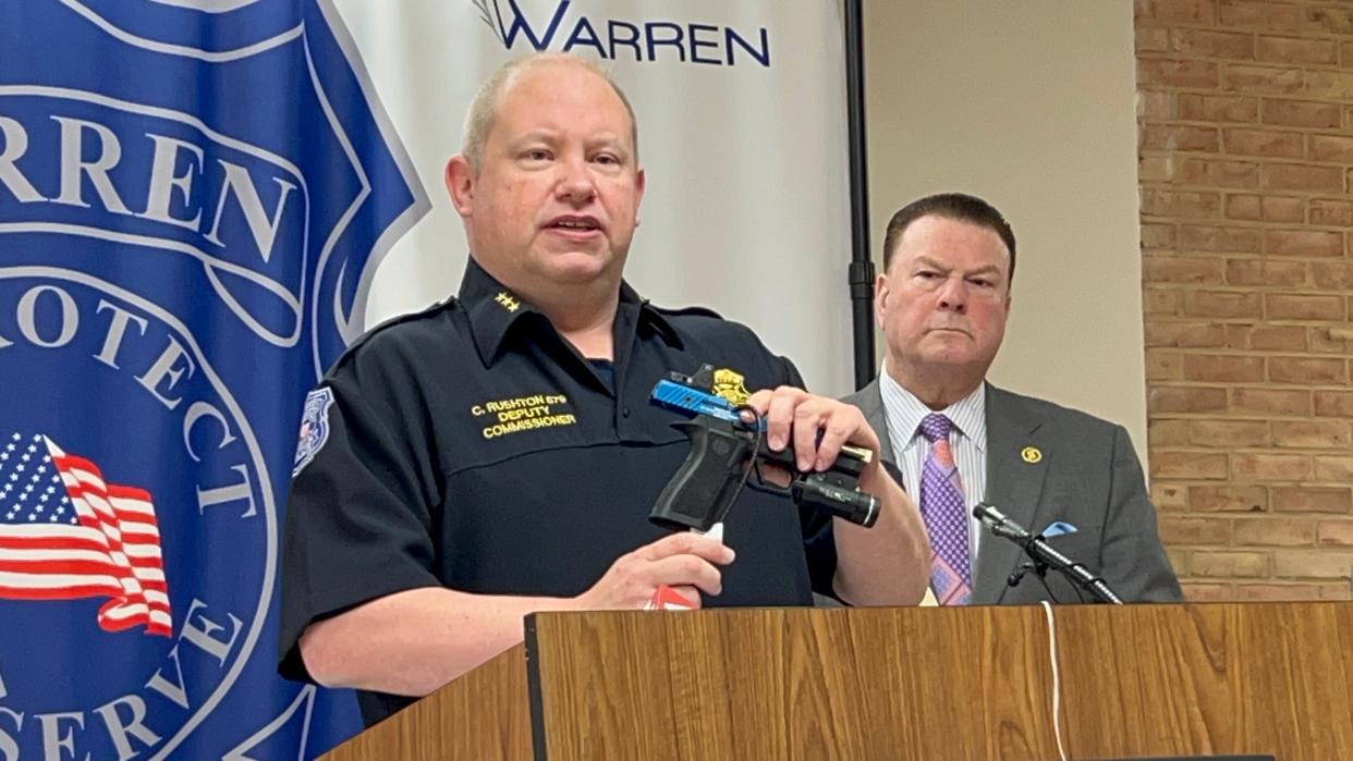 Warren Police Commissioner Charles Ruston demonstrates putting on a gun lock at a news conference at Warren Police headquarters April 24, 2024 with Macomb County Prosecutor Peter Lucido.