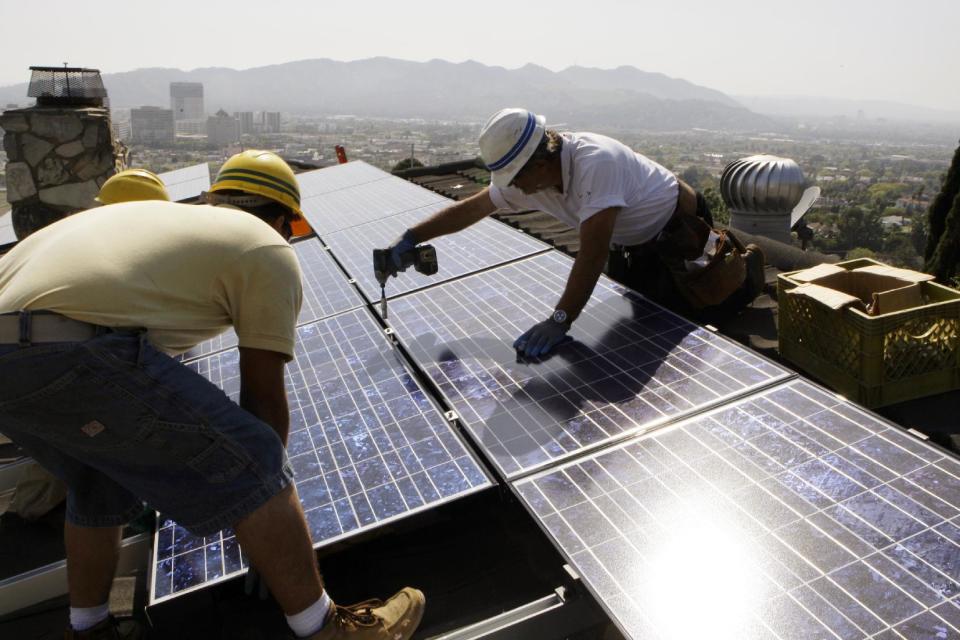 FILE - In this March 23, 2010, file photo, installers from California Green Design install solar electrical panels on the roof of a home in Glendale, Calif. Renewable energy developers say they're hopeful about the future despite President-elect Donald Trump's promise to bring coal mining jobs back. In recent years, huge solar and wind farms have sprouted up on public desert land in the Western United States buoyed by generous federal tax credits. (AP Photo/Reed Saxon, File)