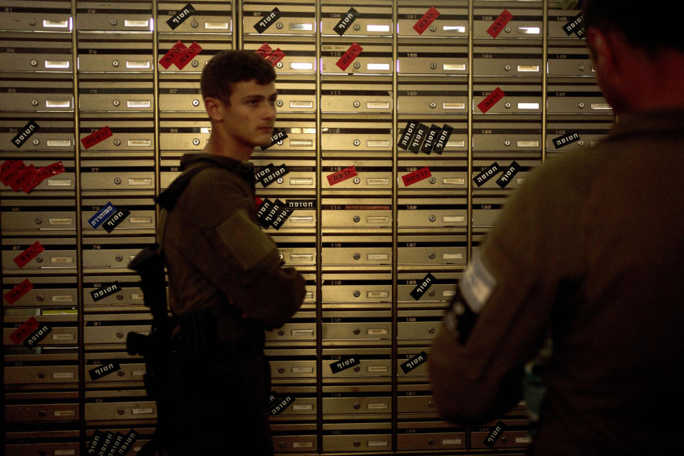 Israeli soldiers visit the mailroom in Kibbutz Nir Oz, where mailboxes are labeled with residents' status - killed (red), kidnapped (black), and released (blue) on Thursday, April 11, 2024, at the communal dining hall during a Passover seder event for hostages held in Gaza, at the kibbutz in southern Israel, where a quarter of all residents were killed or captured by Hamas on Oct. 7, 2023. (AP Photo/Maya Alleruzzo)