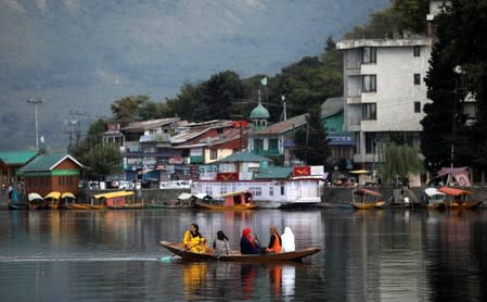 Women row a small boat in the waters of Dal lake in Srinagar