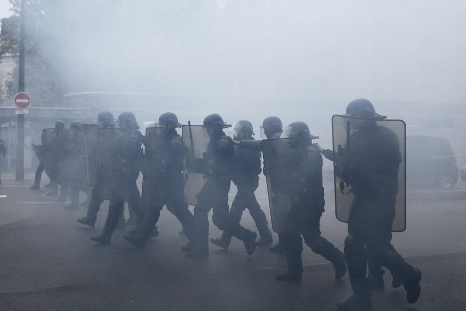French riot police officers run towards demonstrators during a yellow vest demonstration marking the first anniversary in Paris, Saturday, Nov. 16, 2019. Paris police fired tear gas to push back yellow vest protesters trying to revive their movement on the first anniversary of the sometimes violent uprising. (AP Photo/Kamil Zihnioglu)