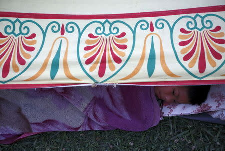 A boy sleeps inside a makeshift shelter in an open ground after an earthquake in Kathmandu, Nepal April 26, 2015. REUTERS/Navesh Chitrakar