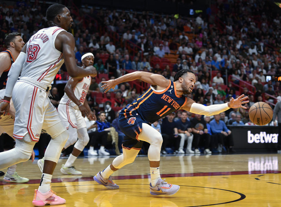 New York Knicks guard Jalen Brunson (11) reaches for the ball in front of Miami Heat center Bam Adebayo (13) during the first half of an NBA basketball game, Wednesday, March 22, 2023, in Miami, Fla. (AP Photo/Michael Laughlin)