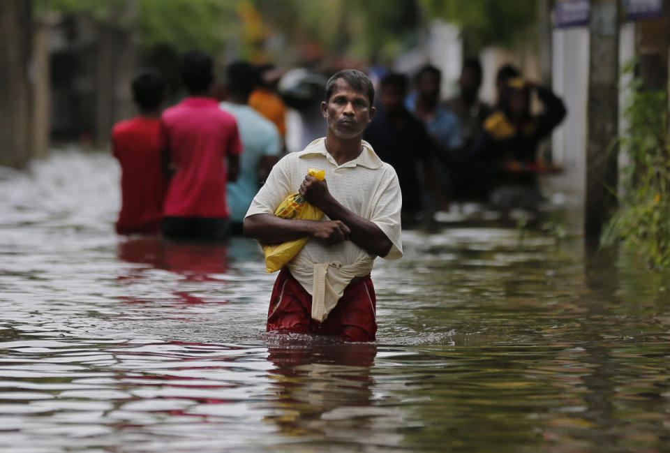 A Sri Lankan man walks through an alley that was flooded following heavy rains in Colombo, Sri Lanka, May 17, 2016. (AP Photo/Eranga Jayawardena)