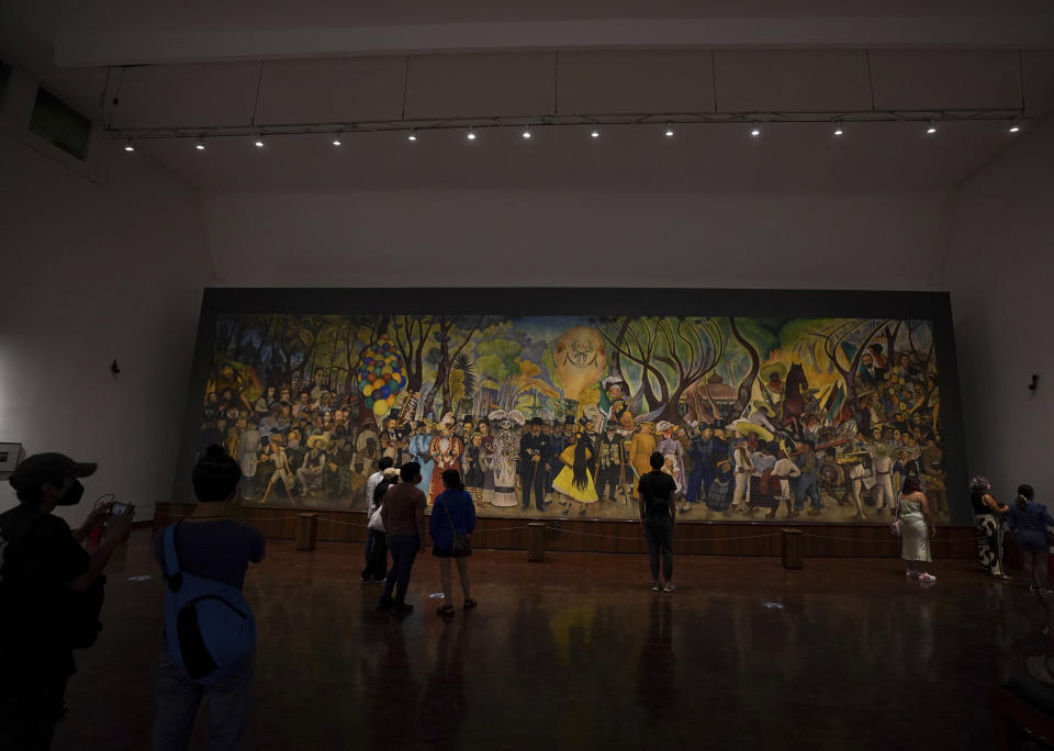 Visitors look at the “Dream of a Sunday afternoon in Alameda Central Park” mural by Mexican artist Diego Rivera at the Diego Rivera Mural Museum, in Mexico City, Sunday, June 5, 2022. (AP Photo/Fernando Llano)