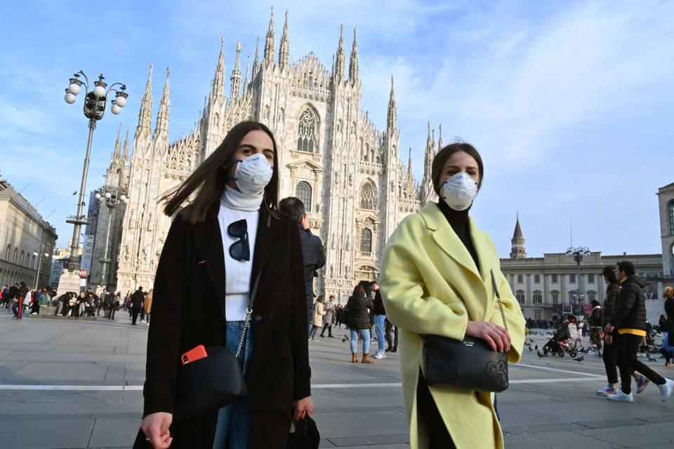 People wearing masks walk across Piazza del Duomo in central Milan (AFP via Getty Images)