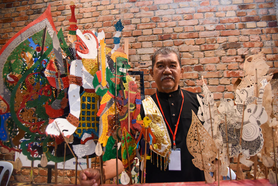 Mohd Jufry Yusoff with the 'wayang kulit' puppets made by him.