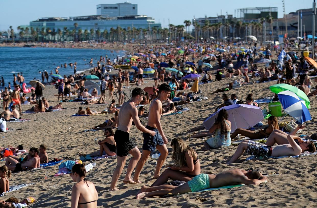 People enjoy the sunny weather at Barceloneta beach, after Catalonia's regional authorities and the city council announced restrictions to contain the spread of the coronavirus disease: REUTERS