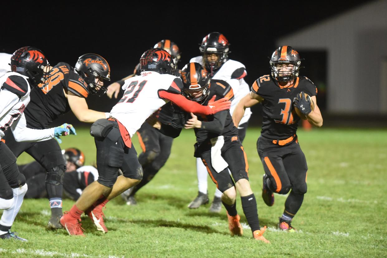 Almont's Chase Battani (32) carries the ball while Chase Davedowski (1) leads with a block during a Division 6 district final against Warren Michigan Collegiate at Almont High School on Friday.