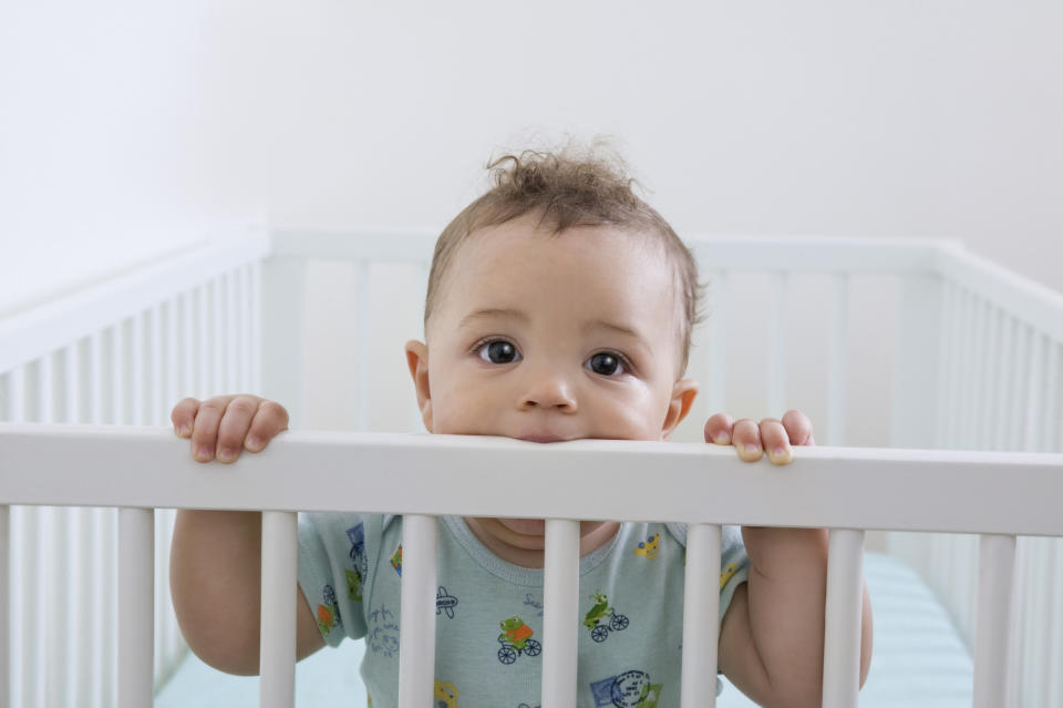 baby with its mouth on the crib