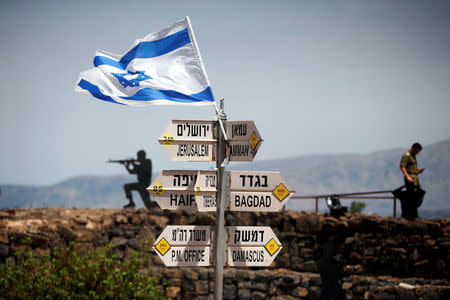 An Israeli soldier stands next to signs pointing out distances to different cities, on Mount Bental, an observation post in the Israeli-occupied Golan Heights that overlooks the Syrian side of the Quneitra crossing, Israel May 10, 2018. REUTERS/Ronen Zvulun