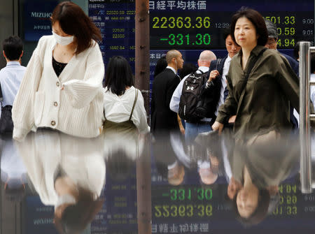 People walk past an electronic board showing Japan's Nikkei average outside a brokerage in Tokyo, Japan, October 15, 2018. REUTERS/Toru Hanai