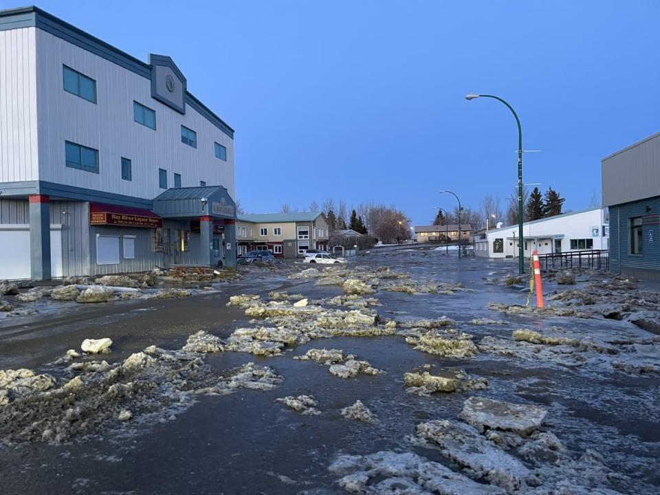 Ice and water sits in a street in Hay River, N.W.T., last week. In an update Sunday afternoon, the town said people not directly involved in the disaster response should stay away.  (Kate Kyle/CBC - image credit)