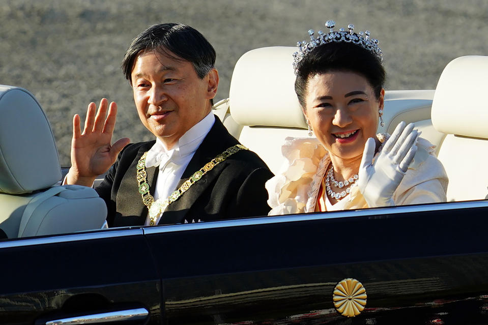 Japanese Emperor Naruhito, left, and Empress Masako, right, wave during the royal motorcade in Tokyo, Sunday, Nov. 10, 2019. (AP Photo/Eugene Hoshiko)