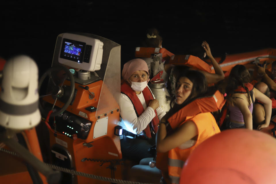 People are evacuated by boat after wildfires reached the Kemerkoy Power Plant, a coal-fueled power plant, in Milas in southwest Turkey, late Wednesday, Aug. 4, 2021. (AP Photo/Cem Tekkesoglu)