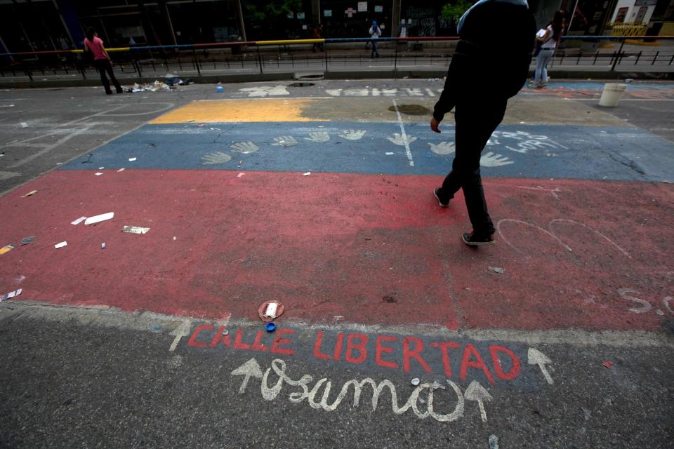 A pedestrian walks on an empty lot that a day before was filled with pitched tents and student protesters, near the United Nations headquarters in Caracas, Venezuela, Thursday, May 8, 2014. Hundreds of security forces broke up four camps maintained by student protesters, arresting 243 people in a Thursday pre-dawn raid. The camps consisting of small tents were installed more than a month ago in front of the UN building and other anti-government strongholds in the capital to protest against President Nicolas Maduro's government. (AP Photo/Fernando Llano)