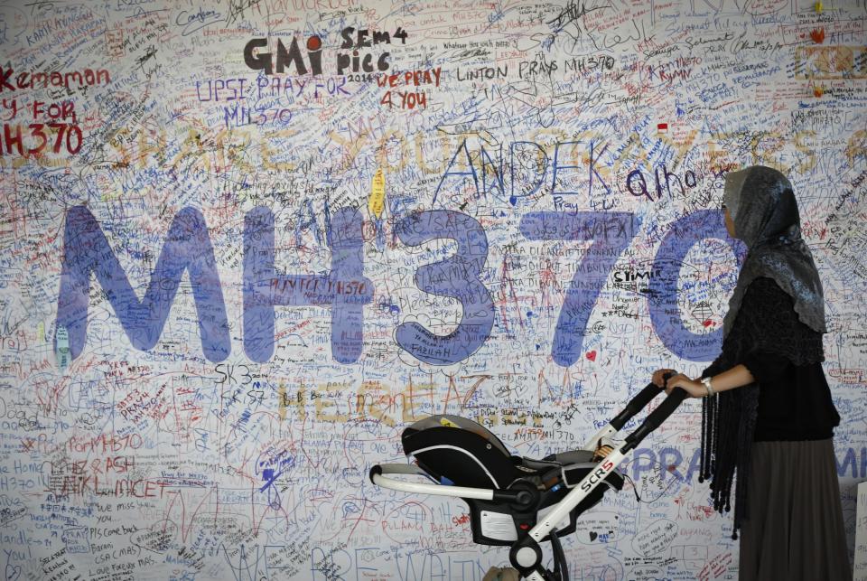 A woman pushes her baby cart in front of the messages board for passengers aboard a missing Malaysia Airlines plane at Kuala Lumpur International Airport in Sepang, Malaysia, Wednesday, March 19, 2014. New radar data from Thailand gave Malaysian investigators more potential clues Wednesday for how to retrace the course of the missing Malaysian airliner, while a massive multinational search unfolded in an area the size of Australia. (AP Photo/Vincent Thian)