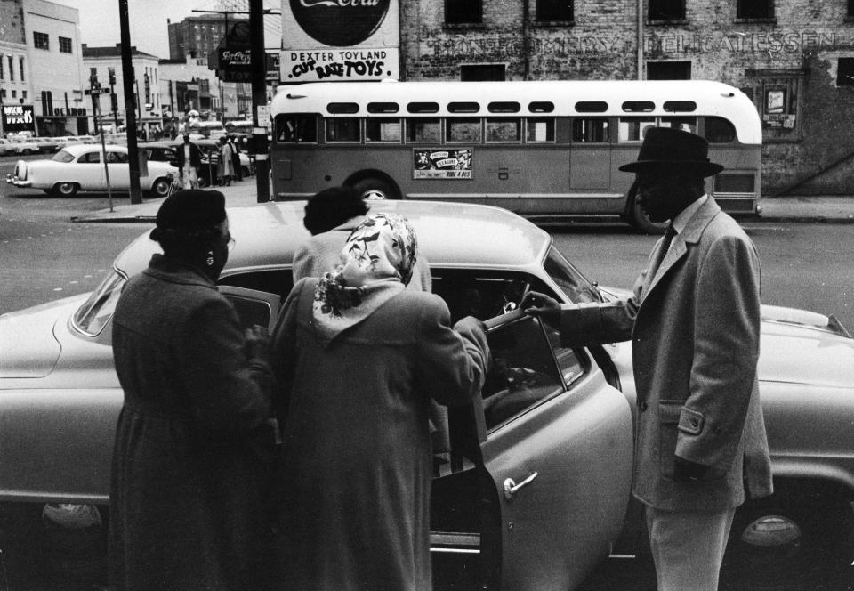  A group of African Americans get into an automobile to car pool during the Montgomery bus boycott, Montgomery, Alabama, February 1956. An empty city bus is visible in the background. 