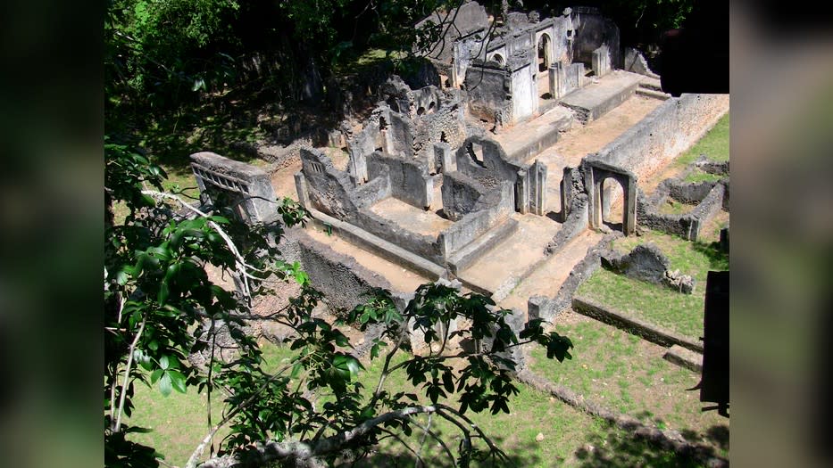 Here we see stone structures and a cemetery amongst trees and grass.