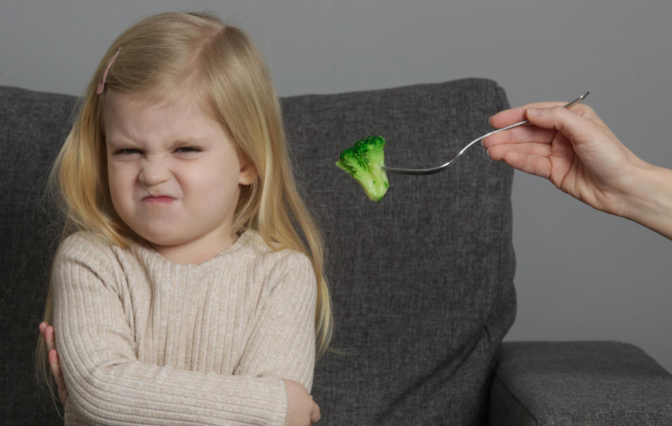 little girl refusing to eat a broccoli